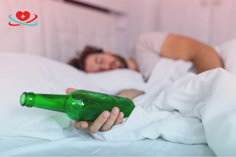 Мужчина лежит на кровати и держит в руке бутылку